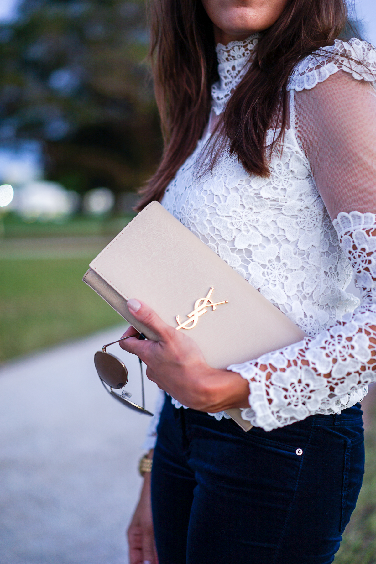 Best Luxury Designers Handbags blogger carrying YSL monogram clutch in a lace blouse