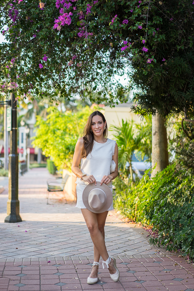 woman in an all white outfit and holding her hat
