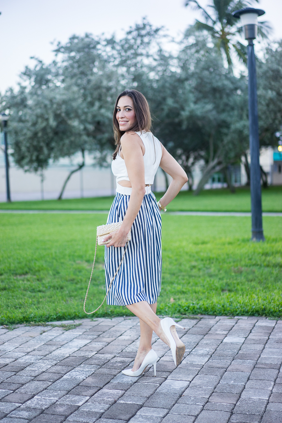 Best Luxury Designers Handbags fashion blogger wearing white crop top with a striped skirt and chanel pearl bag