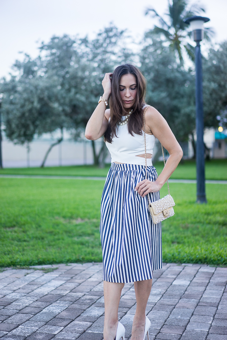 Best Luxury Designers Handbags fashion blogger wearing white crop top with a striped skirt and chanel pearl bag