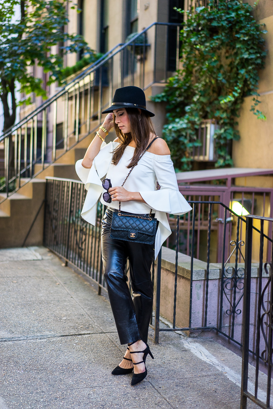 Best Luxury Designers Handbags blogger wearing chicwish white off-the-shoulder top with milly black leather cropped pants and classic chanel bag with a rag and bone fedora and strappy-black-sandals