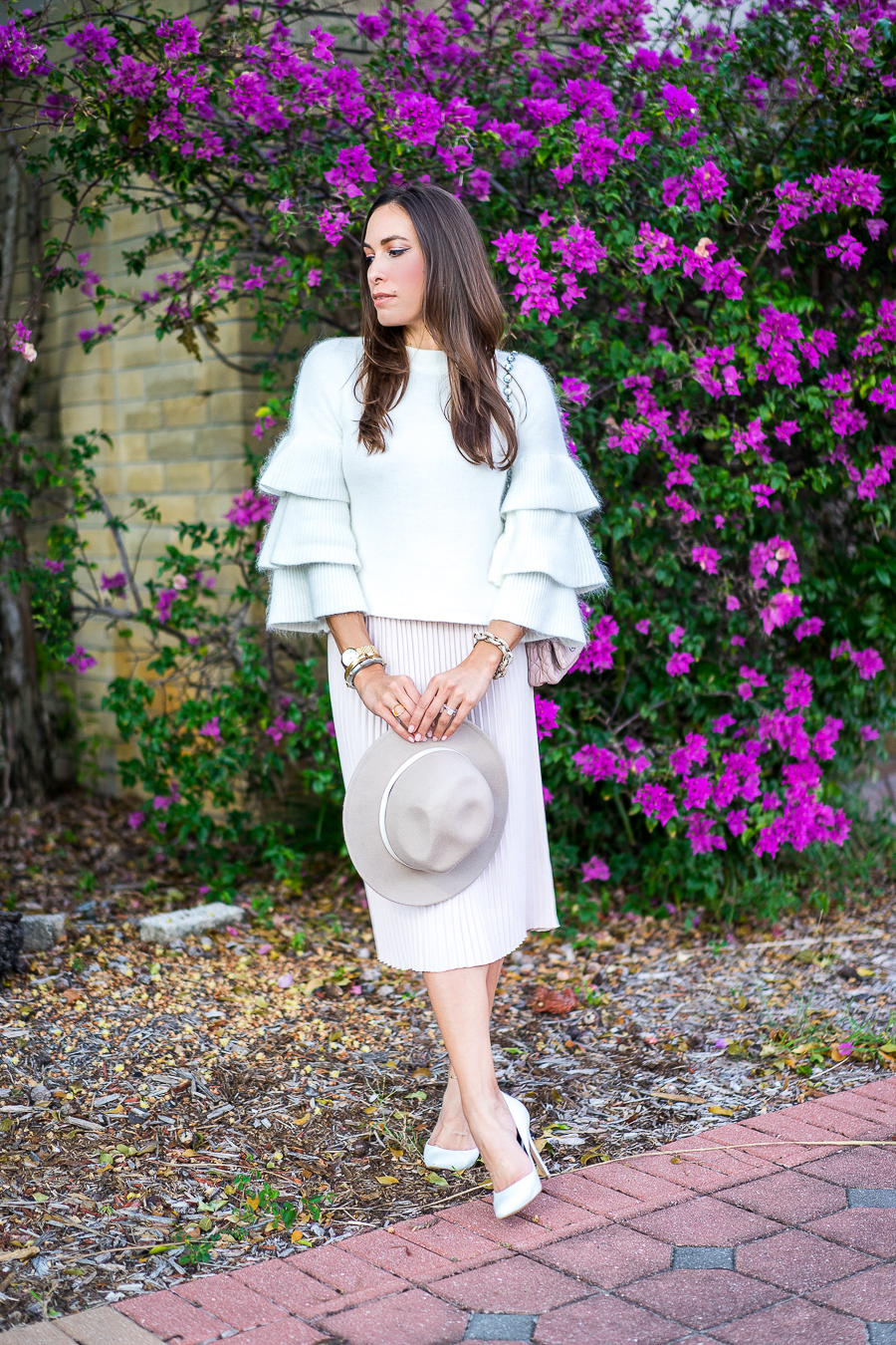 Best Luxury Designers Handbags fashion blogger wearing long sleeved top and blush pleated midi skirt with Miu Miu bag and white pumps