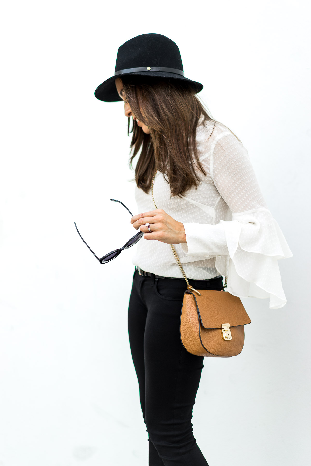 Fashion blogger Amanda who writes Best Luxury Designers Handbags wears Olivia Palermo x Chelsea28 sheer white blouse with Chloe Drew bag dupe and black AG Jeans leggings
