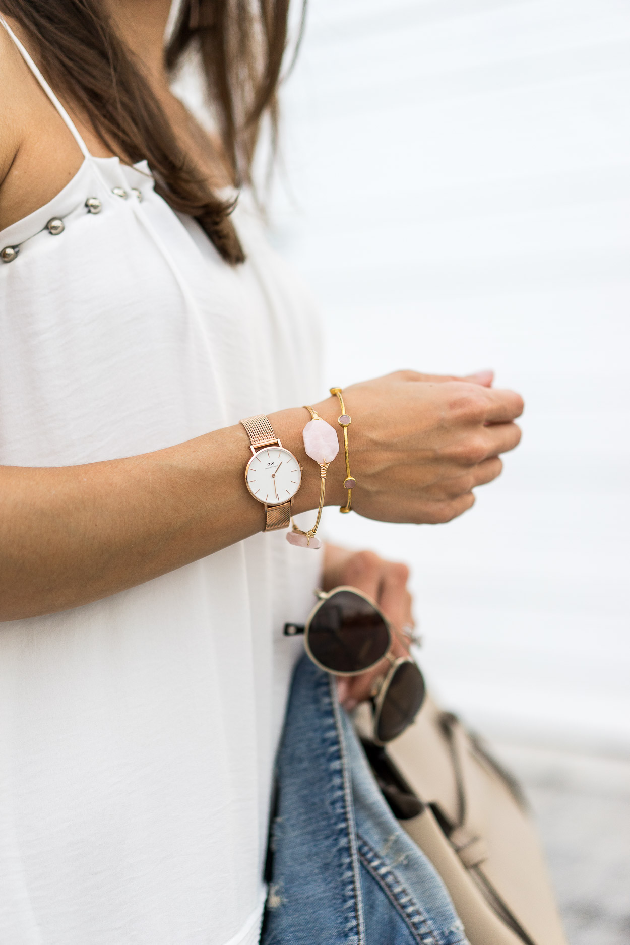  Best Luxury Designers Handbags blogger wearing white dress, with bracelets and a watch, and holding her sunglasses