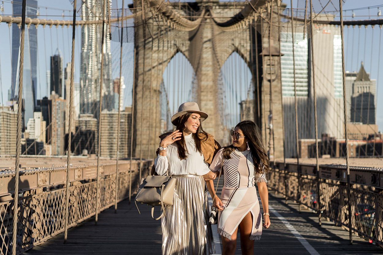 Amanda from Best Luxury Designers Handbags blog styles a metallic pleated skirt with a cream blouse from Aritzia and her Celine belt bag during NYFW with fellow blogger Kelsey Kaplan Fashion