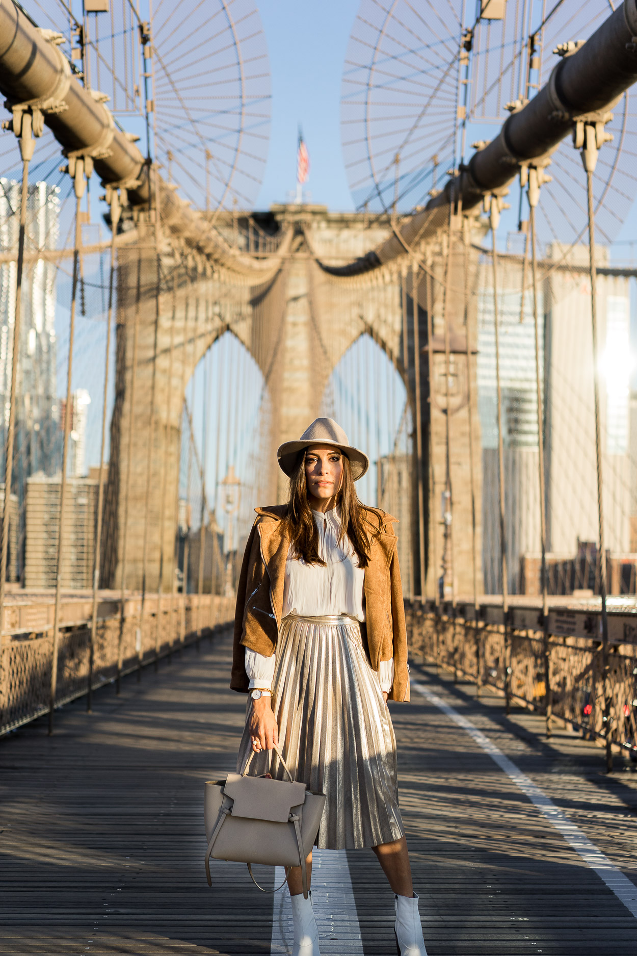 A metallic pleated skirt is trending for Fall and blogger Best Luxury Designers Handbags shares how she styles hers with pretty neutrals like a cream top by Aritzia with a Lulus camel suede jacket and Topshop white ankle booties