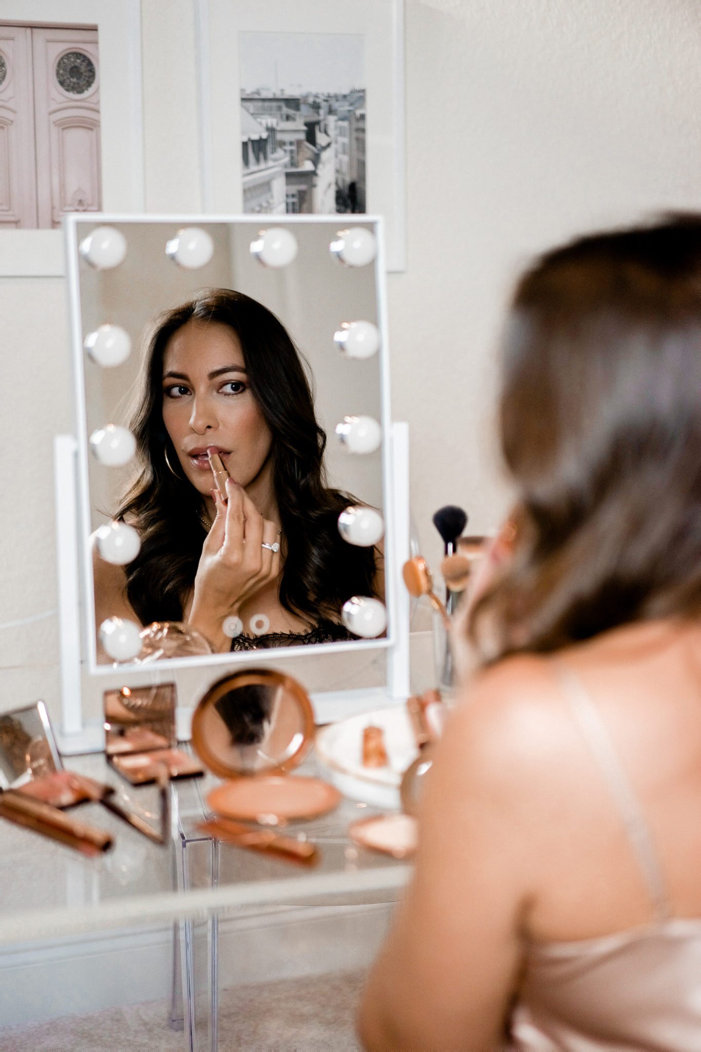 Charlotte Tilbury Favorites: 7 Fall Beauty Essentials by popular Florida beauty blog, Best Luxury Designers Handbags: image of a woman sitting in front of a makeup mirror and applying Charlotte Tilbury makeup. 