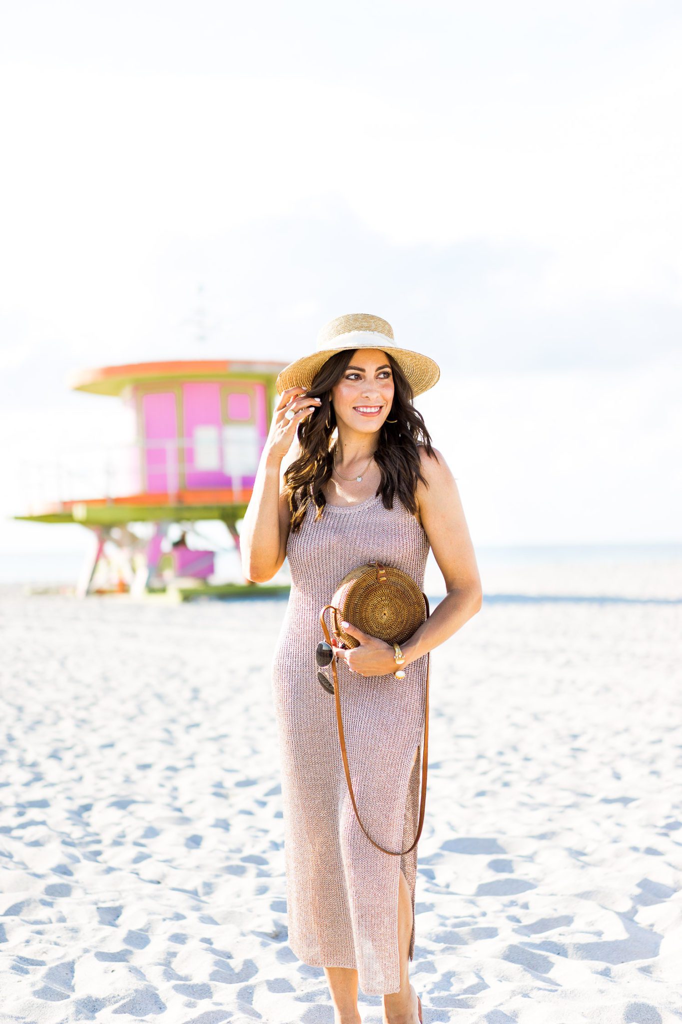 Beach Coverups by popular Florida fashion blog, Best Luxury Designers Handbags: image of a woman walking on the beach and wearing a straw sun hat and Lovers + Friends Fiona Dress. 